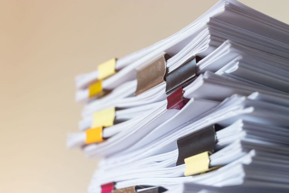 Stapel von Dokumenten mit bunten Büroklammern symbolisieren den Papierkram beim Mieten einer Wohnung in Magdeburg.