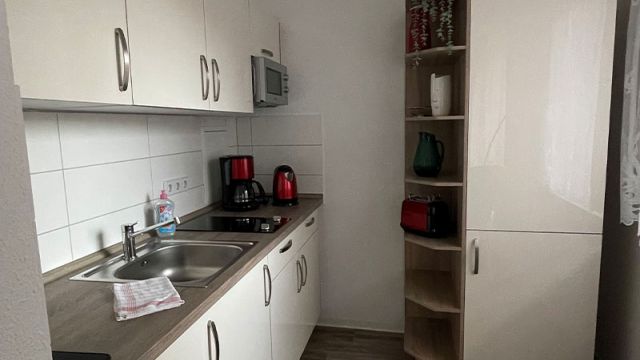 Moderne Küche in einer gemütlichen Wohnung in Magdeburg mit weißen Schränken und Geräten zur Miete.