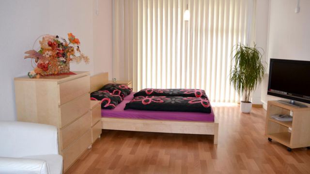 Modernes Schlafzimmer in Magdeburg mit Doppelbett, Kommode und TV, ideal zum Mieten in der Zollstraße.