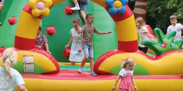 Kinder spielen fröhlich auf einer bunten Hüpfburg in Magdeburg, während die Sonne scheint und Spaß macht.