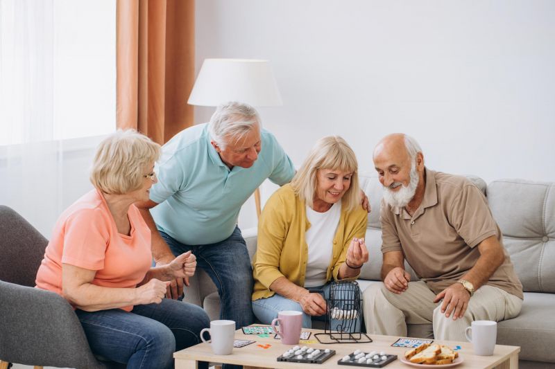 Eine Gruppe älterer Menschen spielt Bingo in einer gemütlichen Wohnung in Magdeburg.