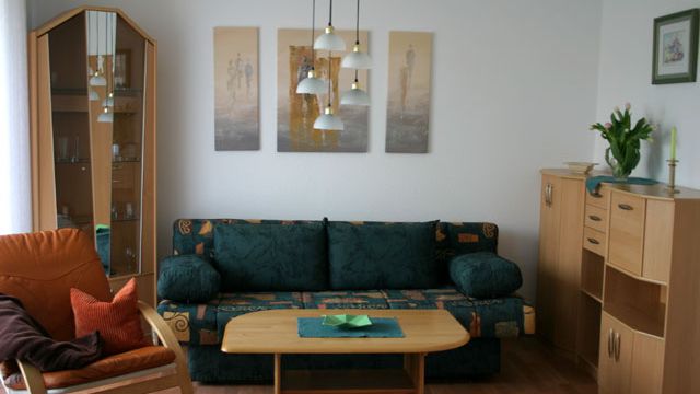 Gemütliches großes Wohnzimmer mit grüner Couch und stilvollen Holzmöbeln in einer Mietwohnung in Magdeburg.