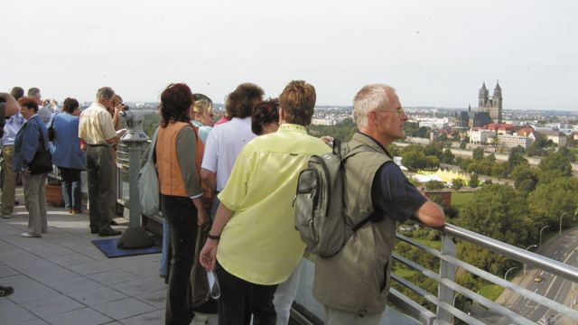 Besucher genießen den Ausblick auf Magdeburg und denken über das Mieten einer Wohnung in der Nähe des Doms nach.