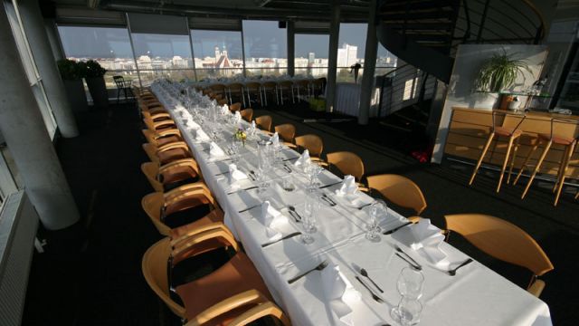 In einer geräumigen Wohnung in Magdeburg steht eine lange gedeckte Tischreihe vor großen Fenstern mit Stadtblick.